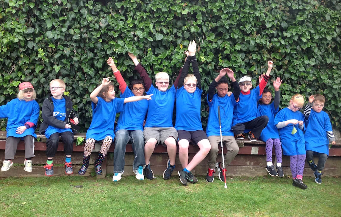 11 children sitting along a bench