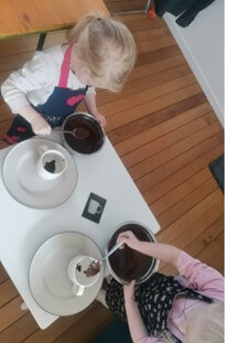 2 girls at a table making a cake in a cup.