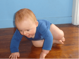 A baby crawling on a hard floor.