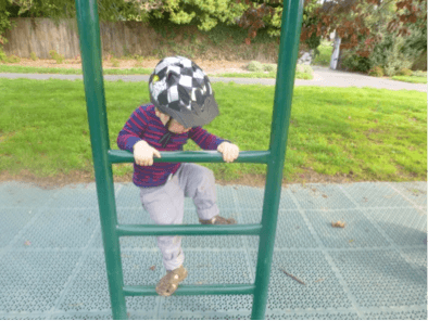 A child climbing up the steps of a ladder in a playground.