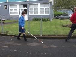 A learner is travelling confidently around her school using her cane.