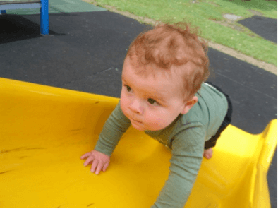 A young child climbing up a playground slide.