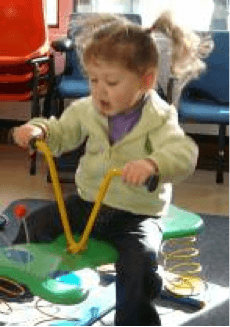 A young child playing on a spring rocker.