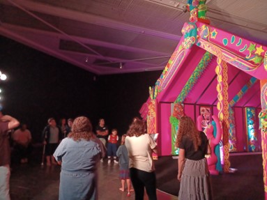Ākonga and whānau standing in front of the wharenui and listening to a description about what is represented on the front panels.