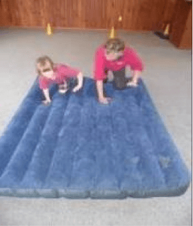 Child and O & M instructor crawling on an airbed.