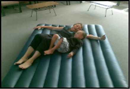 Child and adult laying on an airbed, playing.