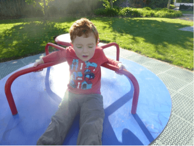 Child spinning on a playground carousel.