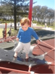Child walking on a balancing trampoline at a playground.
