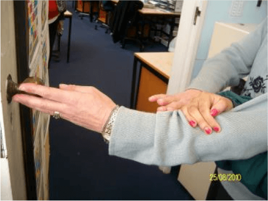 Guide's hand connecting with the door handle. Guide's other hand and person with vision impairment's hand on the guide's arm.