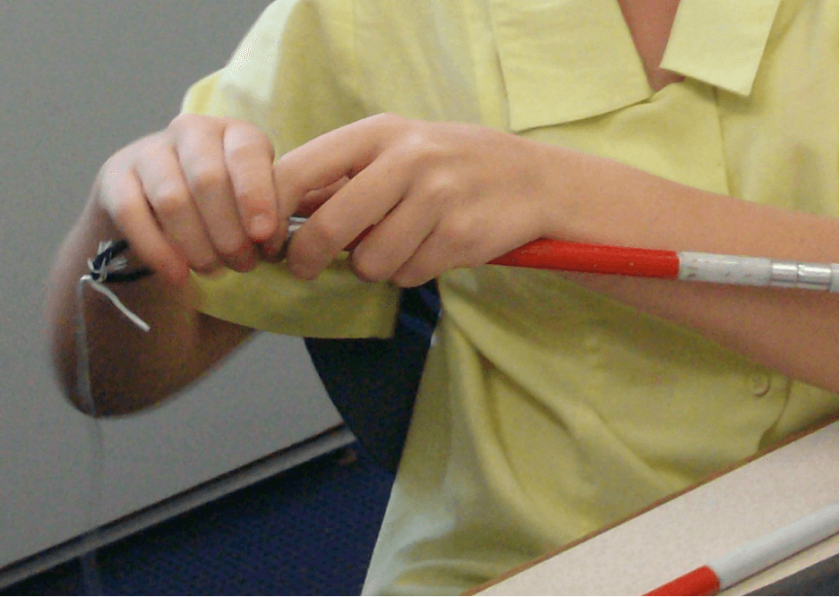 Jesse has the elastic through the cane ready to cut the string off.