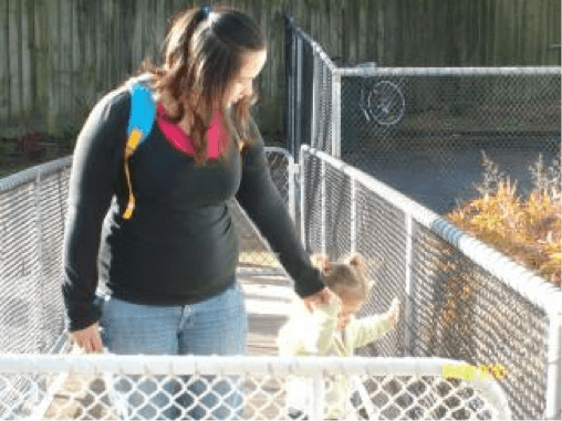 Mum with her toddler using guiding to encourage the toddler to trail the fence.