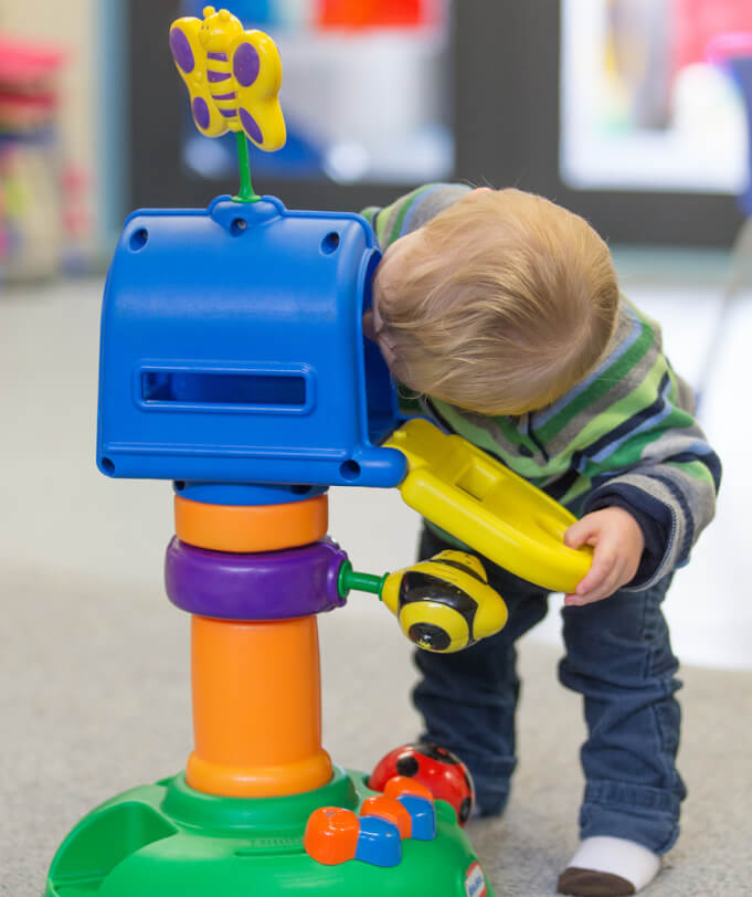 Robert bends over to look inside a toy letterbox.