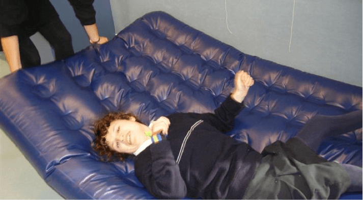 Sam is smiling and lying on the airbed.