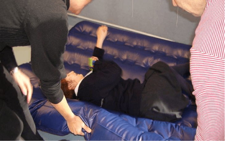 Student lying on the airbed and the O & M Specialist is lifting the airbed edge.