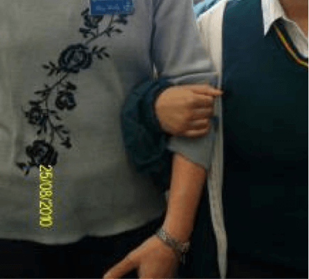 Student with their arm linked around adult peer's elbow.