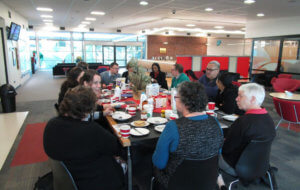 13 staff enjoying breakfast and talking around a dining table