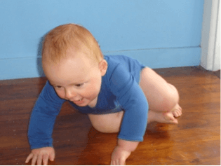 A baby crawling on a hard floor