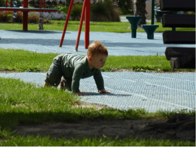 A child crawling on soft matting in a playground