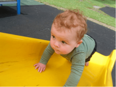 A young child climbing up a playground slide