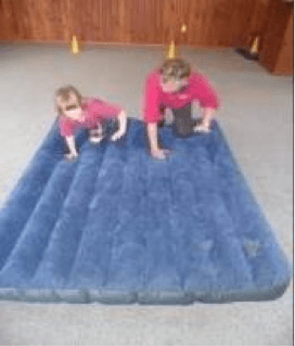 Child and O & M instructor crawling on an airbed