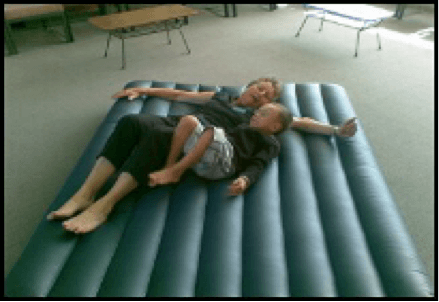 Child and adult laying on an airbed, playing