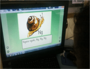 Child looking at computer with 'ng' and snail on the screen