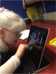 Child sitting looking at and touching her iPad