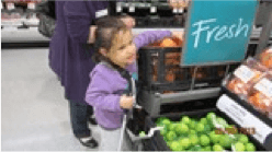 Child standing reaching in to fruit bin at supermarket