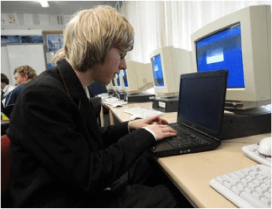 Student sitting in a computer suite working on a laptop