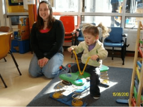 Toddler child sitting on a bouncy spring caterpillar toy with mum sitting to her right