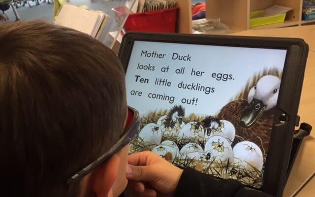 Child reading iPad for story in large print
