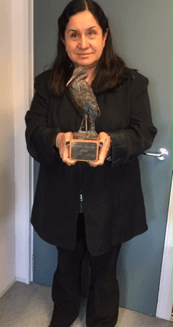 Maria Stevens stands holding the Barbara Armitage Award