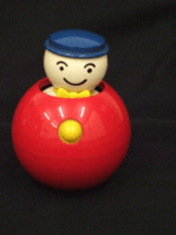 A round plastic ball with a push down figure and a knob to activate