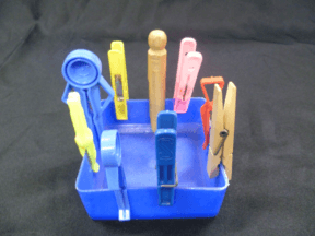 nine clothes pegs of different types pegged to the side of an ice cream container, wooden or plastic push or spring loaded action