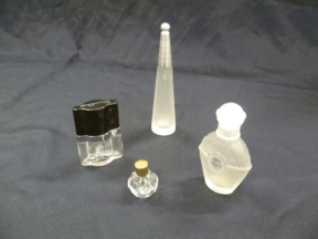 Four perfume bottles of different shapes and sizes with lids