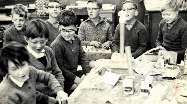 Eight children sitting around a table of tactile model made from boxes and cardboard tubes