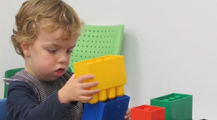 A young boy is attempting to stack duplo blocks together