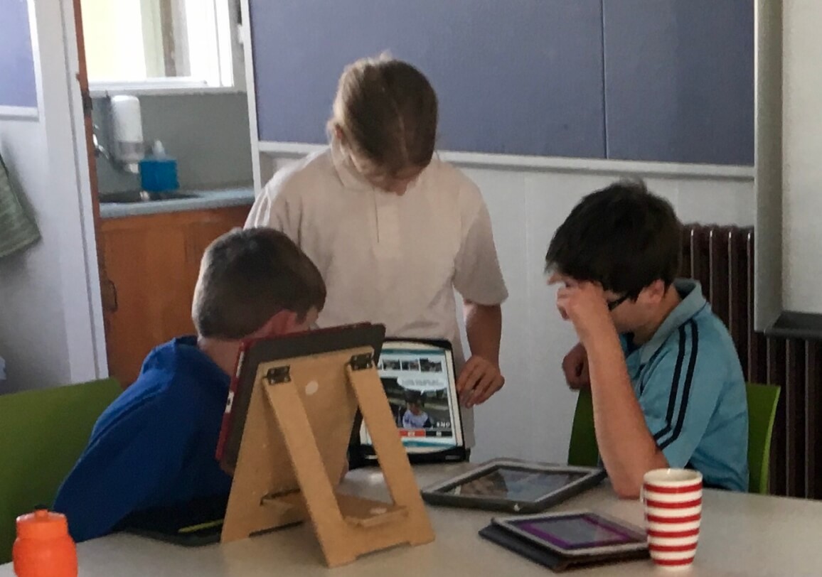 Three children around an iPad looking at the screen