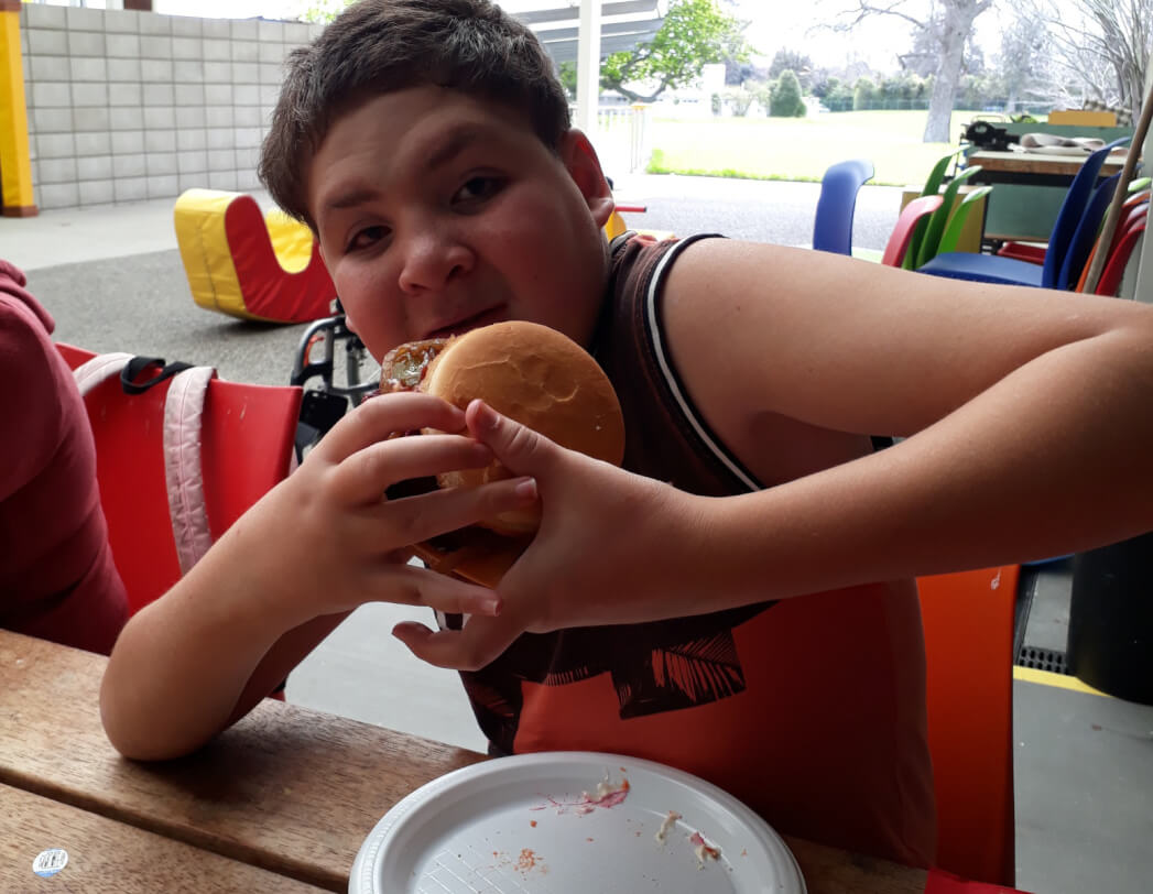 Bradley is facing the camera and holding up his burger about to take his first bite!