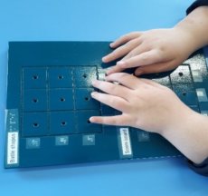 A student using a tactile ships board with with their fingers