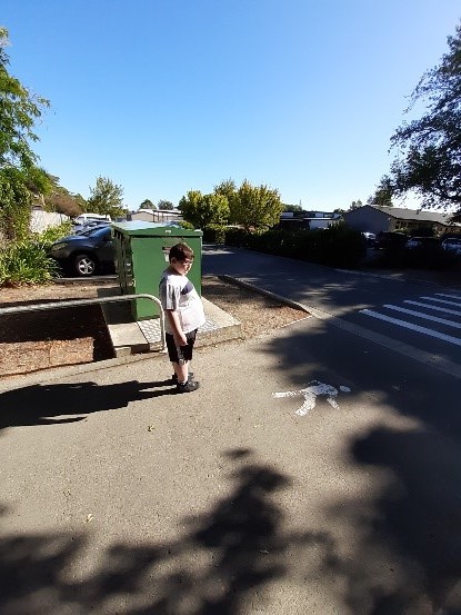 Child is standing at a crossing and using a landmark to assist safe navigation