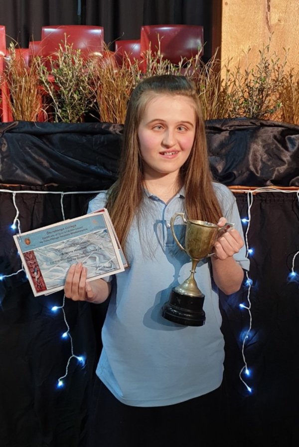 Figure 1 - A student is holding several certificates and a cup prize that she received at prizegiving ceremony at school
