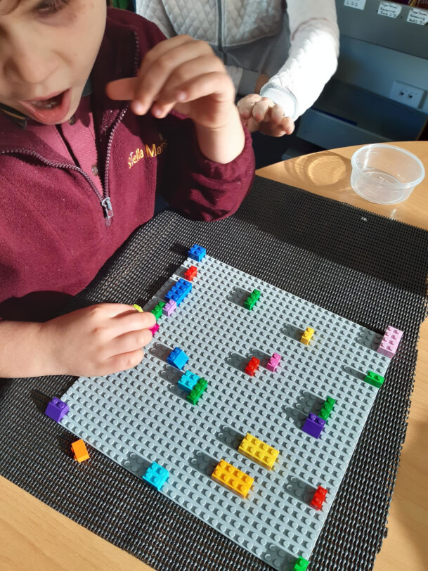 Figure 1 - A young boy places LEGO bricks on the base plate to decorate a pretend cake