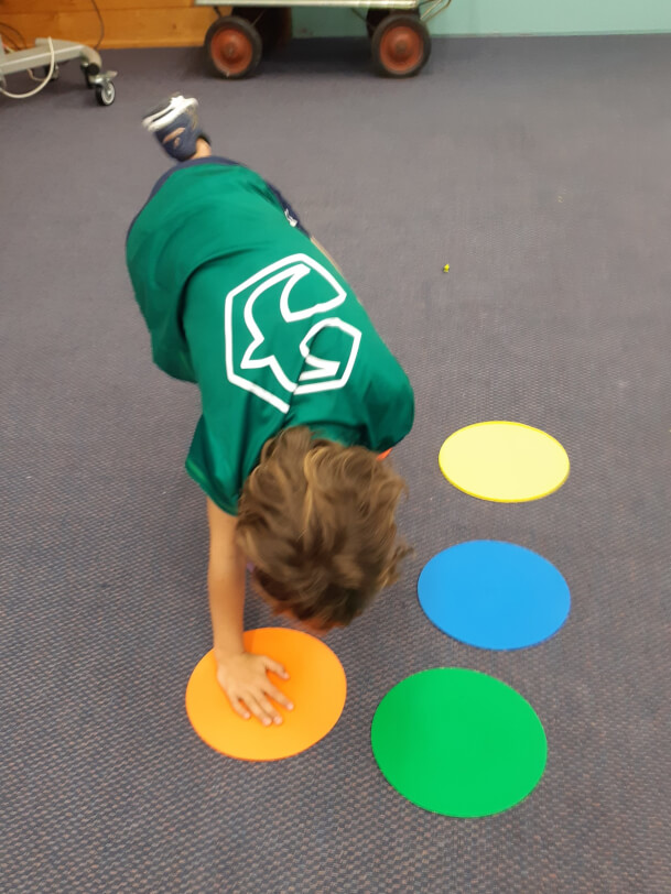 Figure 2 - A boy balances as he places one hand and one foot on two of the six large floor discs