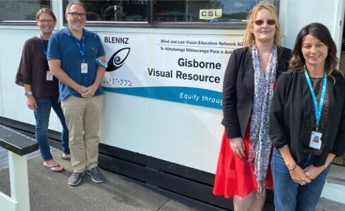 Figure 1 - Gisborne staff standing beside the Gisborne sign on the building