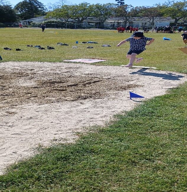 Figure 1 - Laura is making a jump on the long jump track on the grass and sand