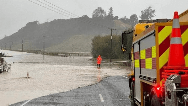 Figure 1 -A person is standing in water on the state highway near Tokomaru Bay submerged as flooding hit the area in March 2023. A fire truck is also on the road.