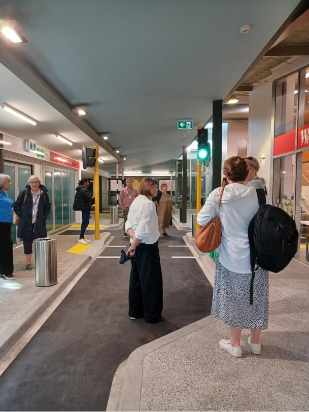 Figure 2 - Nine adults talking to each other, while exploring the traffic lights, escalator, lifts, bus and train at the mobility centre at BLVNZ 
