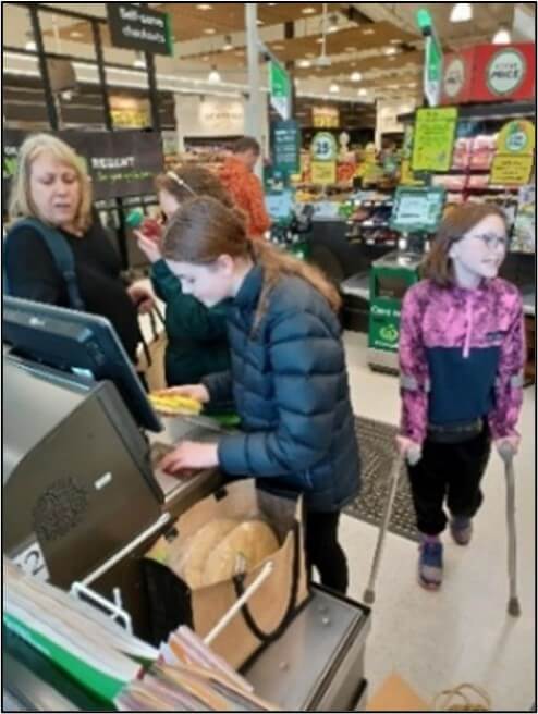 Figure 2 - Zaria using the self-checkout machine at the supermarket to purchase grocery items with Jayne's support